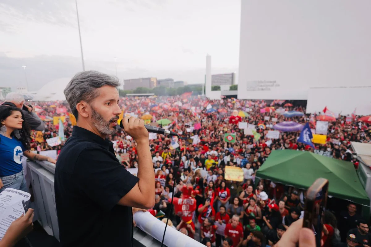 Leandro Grass fala ao microfone com estudantes e manifestantes