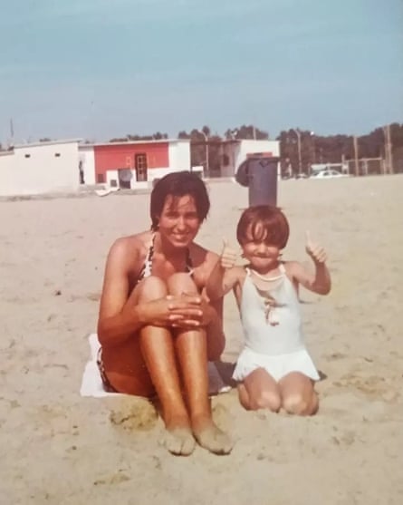 A woman and a young girl in swimsuits on a deserted beach somewhere sunny