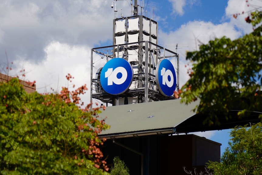 Sign of the number 10 in a blue circle on a tower with trees visible